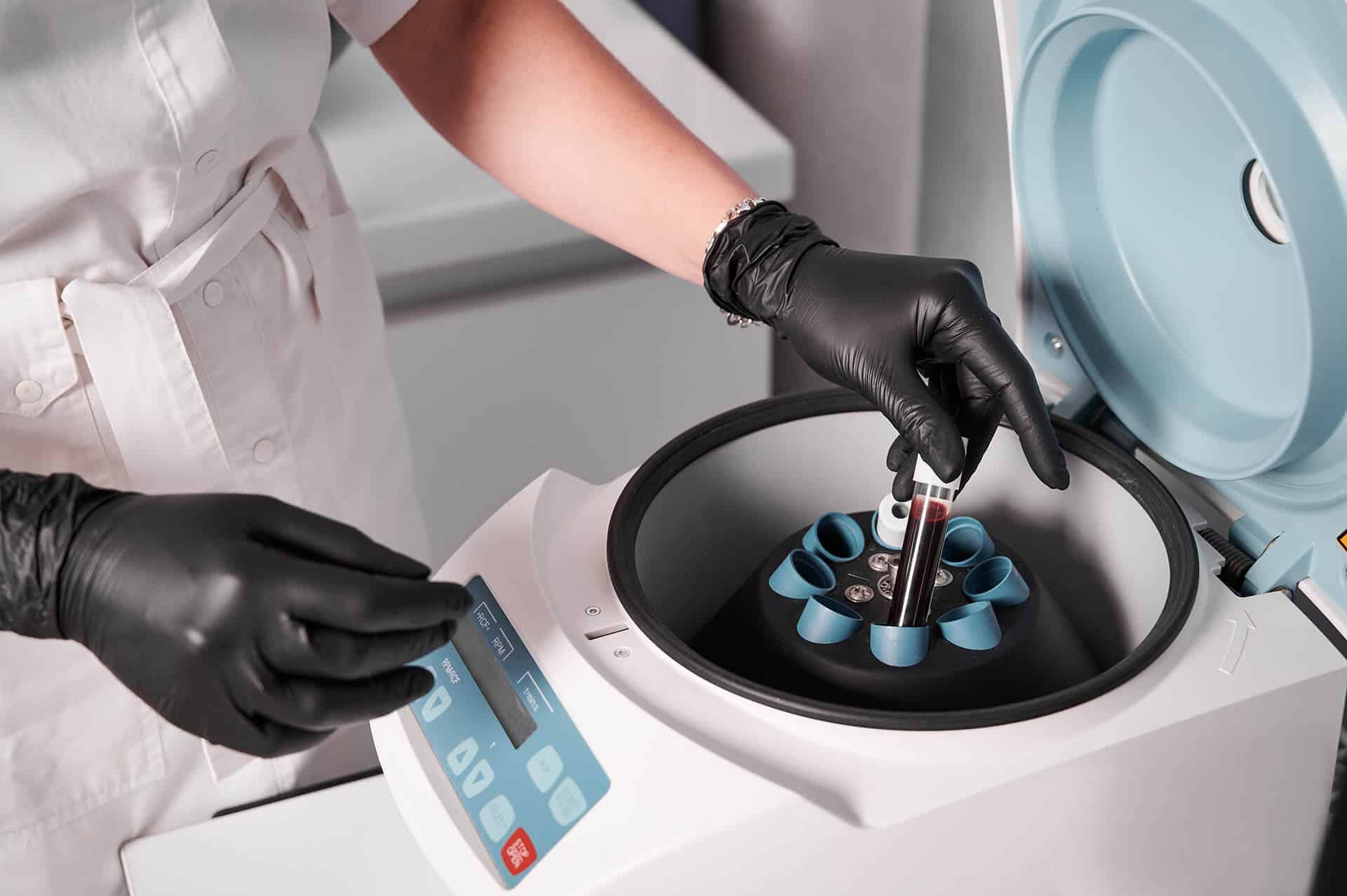 researcher putting test tube into laboratory centrifuge 1