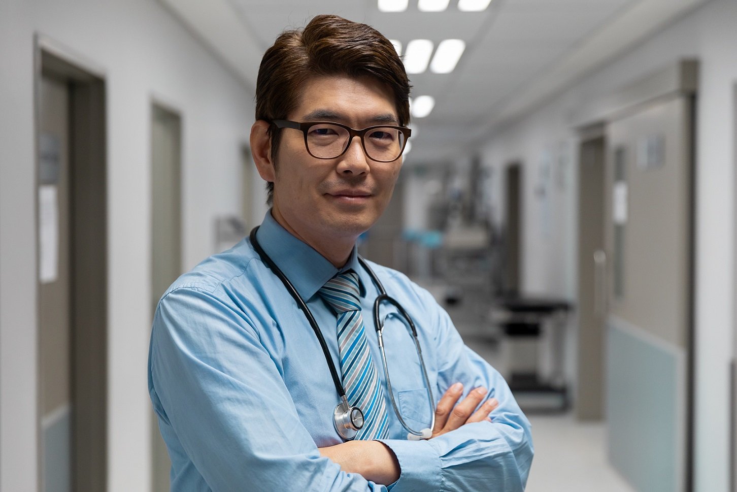 Portrait of mixed race male doctor standing in hospital corridor. medicine, health and healthcare services.